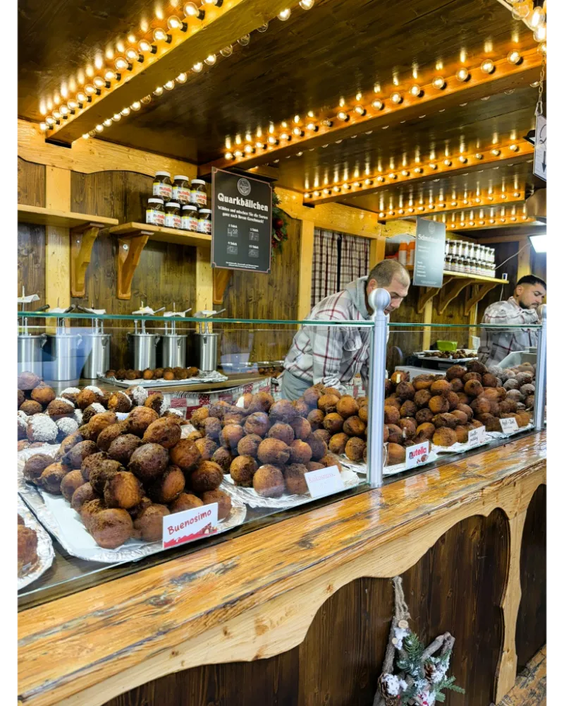 Fresh Quarkbällchen dusted with sugar at the Frankfurt Christmas Market — soft German-style fried dough with a creamy center.